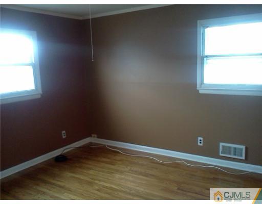 19 Wilshire Road Edison, NJ 08817 - Photo 3 of 7 an empty room with wooden floor and windows