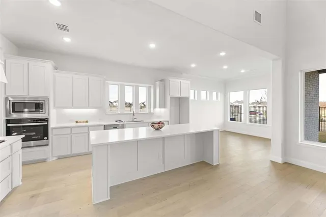 a kitchen with stainless steel appliances a sink cabinets and wooden floor