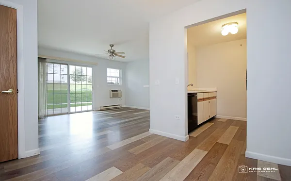 a view of empty room with wooden floor and fan