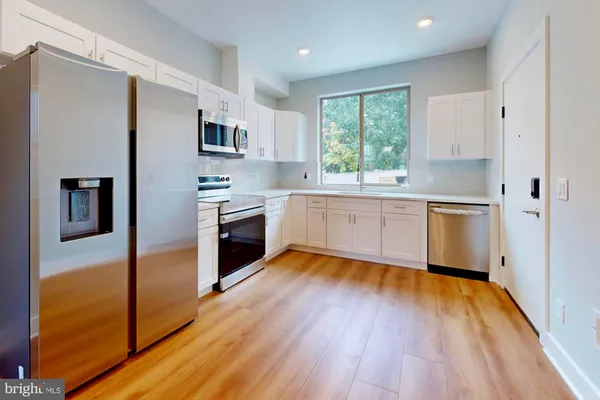 a kitchen with stainless steel appliances granite countertop wooden floors and white cabinets