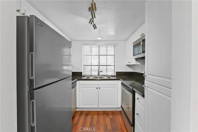 a kitchen with granite countertop stainless steel appliances a sink stove and cabinets