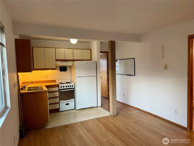 a kitchen with granite countertop a refrigerator stove and wooden floor
