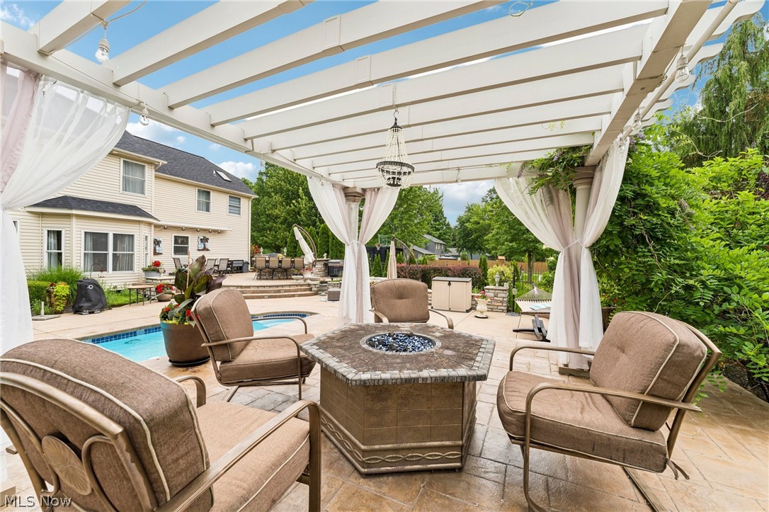 8874 Sharp Road Olmsted Falls, OH 44138 - Photo 23 of 42 Expansive outdoor living area featuring a white pergola, stamped concrete patio, and a built-in fire pit