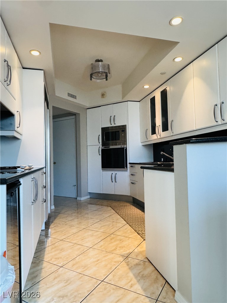 2857 Paradise Road, Unit 904 Las Vegas, NV 89109 - Photo 7 of 27 Kitchen with dark countertops, recessed lighting, white cabinets, oven, and a tray ceiling