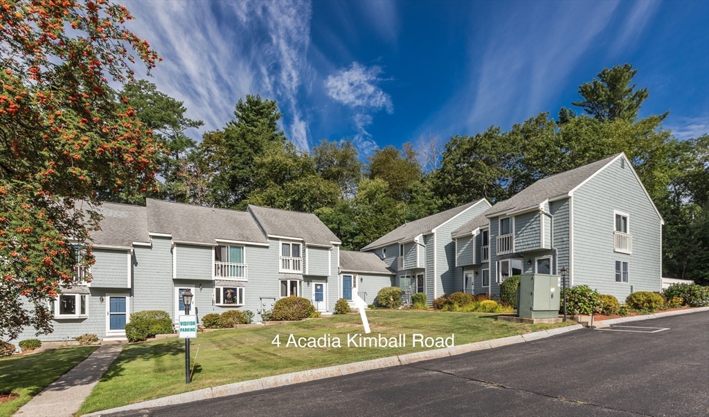 4 Acadia Kimball Road, Unit 4 Amesbury, MA 01913 - Photo 1 of 20 a view of a white house next to a yard with plants and large trees