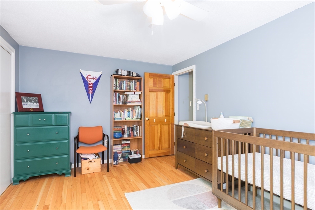 4 Acadia Kimball Road, Unit 4 Amesbury, MA 01913 - Photo 12 of 20 a bedroom with a baby bed a desk and chair with the wooden floor