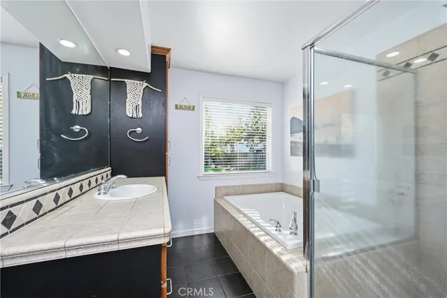 a bathroom with a tub a sink and mirror