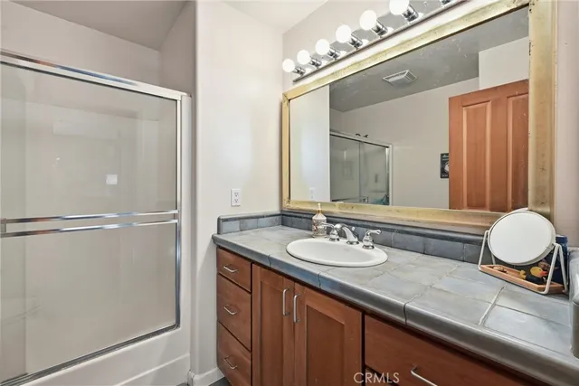 a bathroom with a granite countertop sink mirror and a shower
