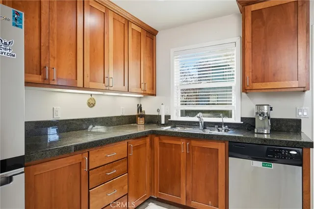 a kitchen with granite countertop stainless steel appliances a sink window and cabinets