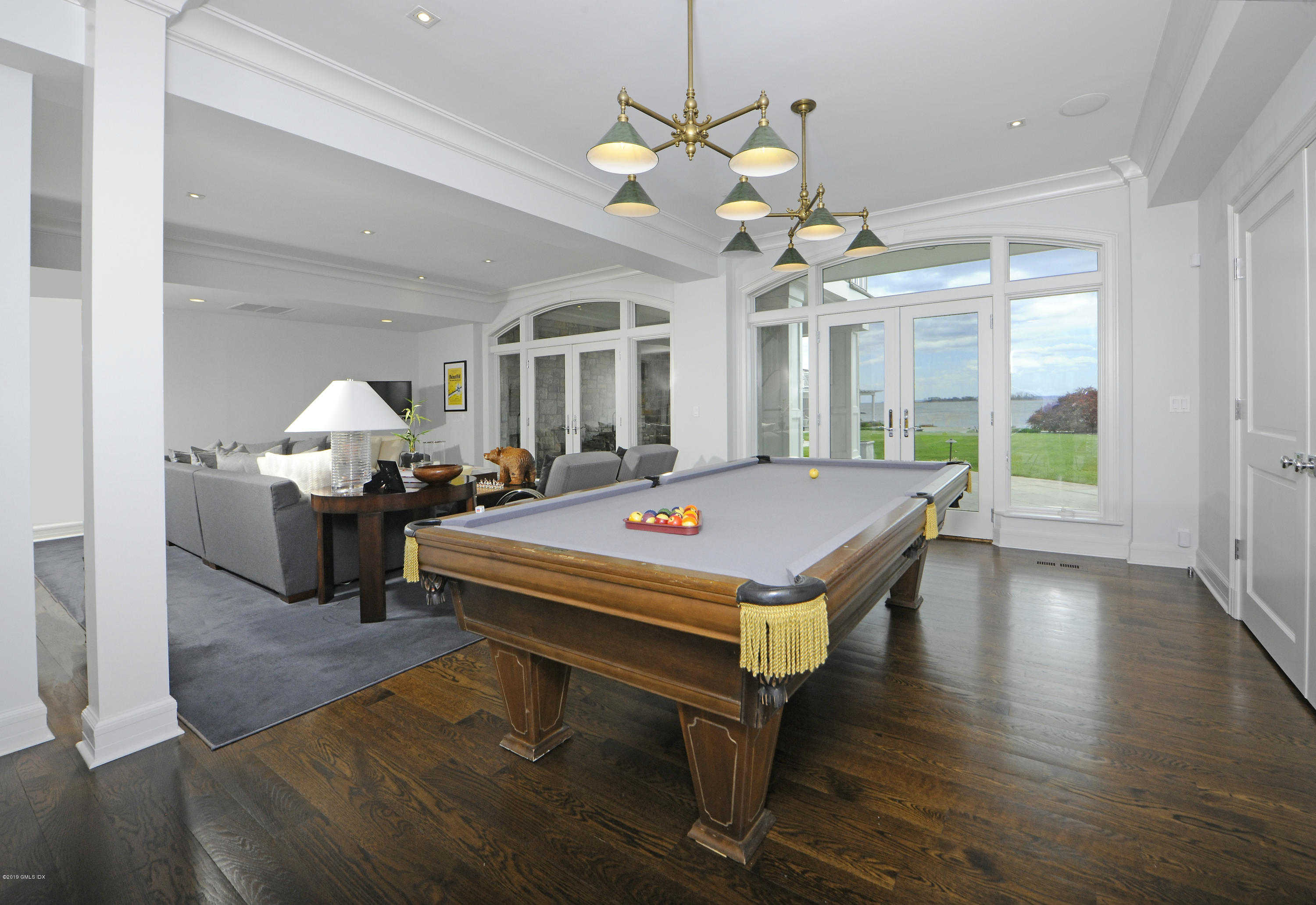 215 Byram Shore Road Greenwich, CT 06830 - Photo 17 of 26 a living room with a dining table couches a chandelier and wooden floor