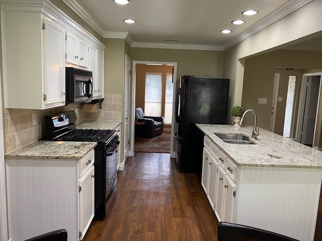 1002 Creekbend Cove Pflugerville, TX 78660 - Photo 10 of 16 Kitchen with white cabinets, light stone countertops, black appliances, crown molding, and dark wood-style floors