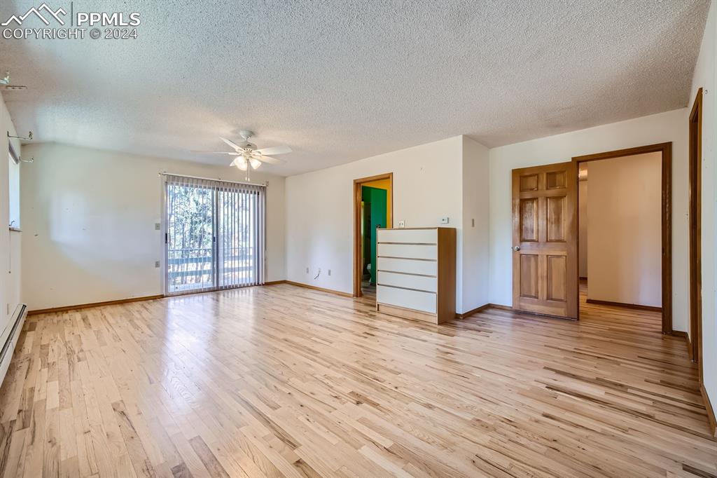 11330 Holmes Road Colorado Springs, CO 80908 - Photo 12 of 40 Empty room with a textured ceiling, light wood-type flooring, and ceiling fan