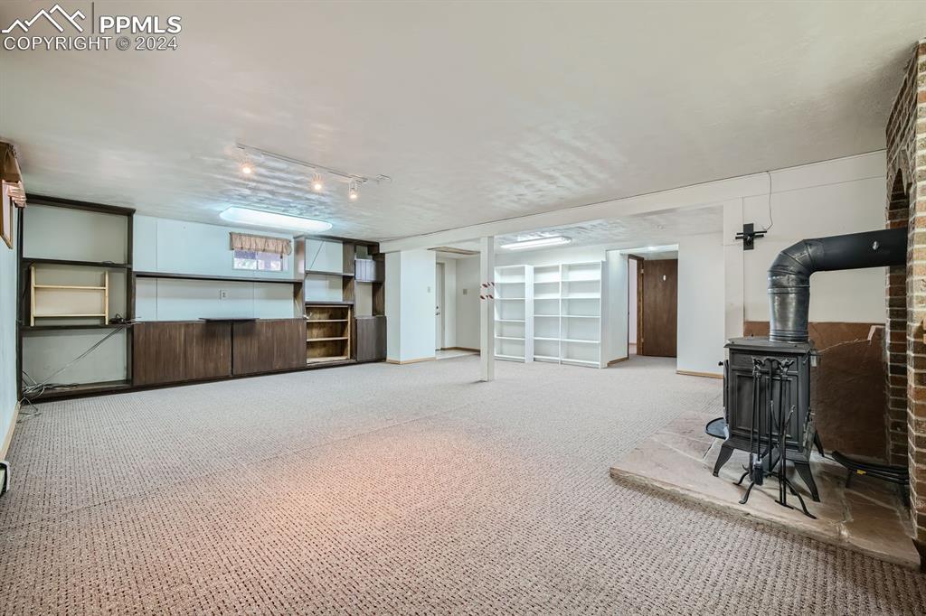 11330 Holmes Road Colorado Springs, CO 80908 - Photo 18 of 40 Carpeted living room with track lighting and a wood stove