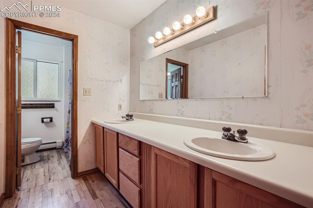 11330 Holmes Road Colorado Springs, CO 80908 - Photo 20 of 40 Bathroom featuring vanity, hardwood / wood-style floors, a baseboard heating unit, and toilet