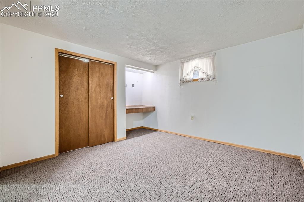 11330 Holmes Road Colorado Springs, CO 80908 - Photo 21 of 40 Unfurnished bedroom featuring a textured ceiling, a closet, and carpet flooring