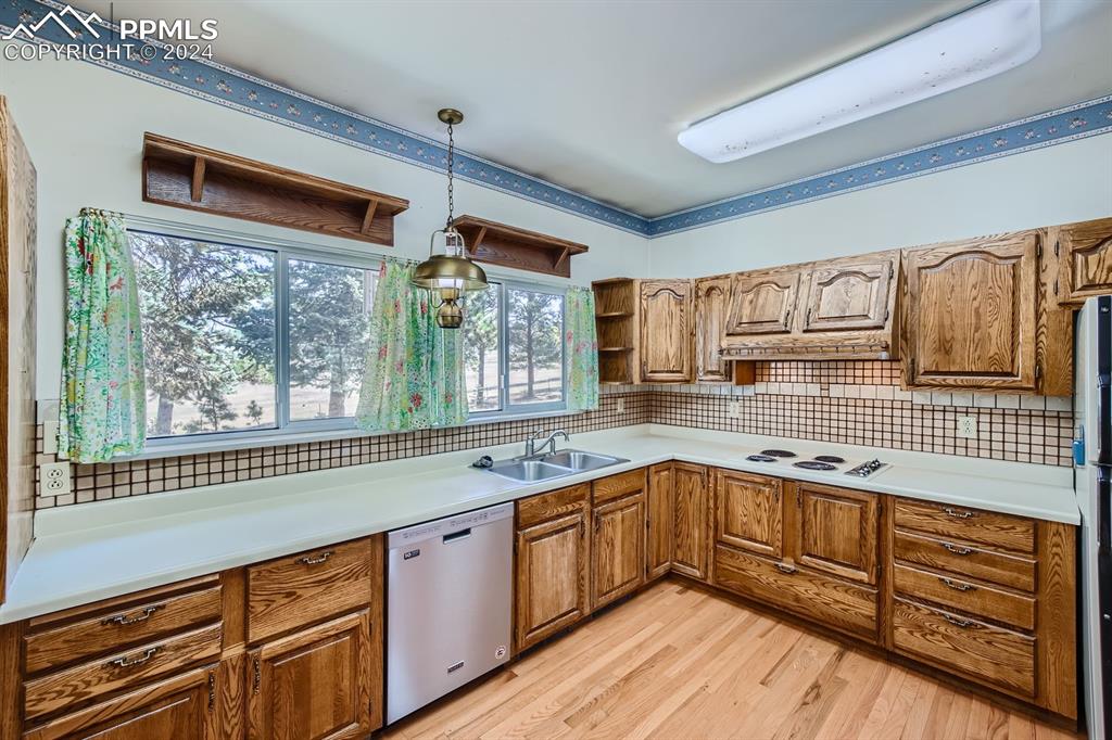 11330 Holmes Road Colorado Springs, CO 80908 - Photo 7 of 40 Kitchen with tasteful backsplash, stainless steel dishwasher, light hardwood / wood-style flooring, pendant lighting, and sink