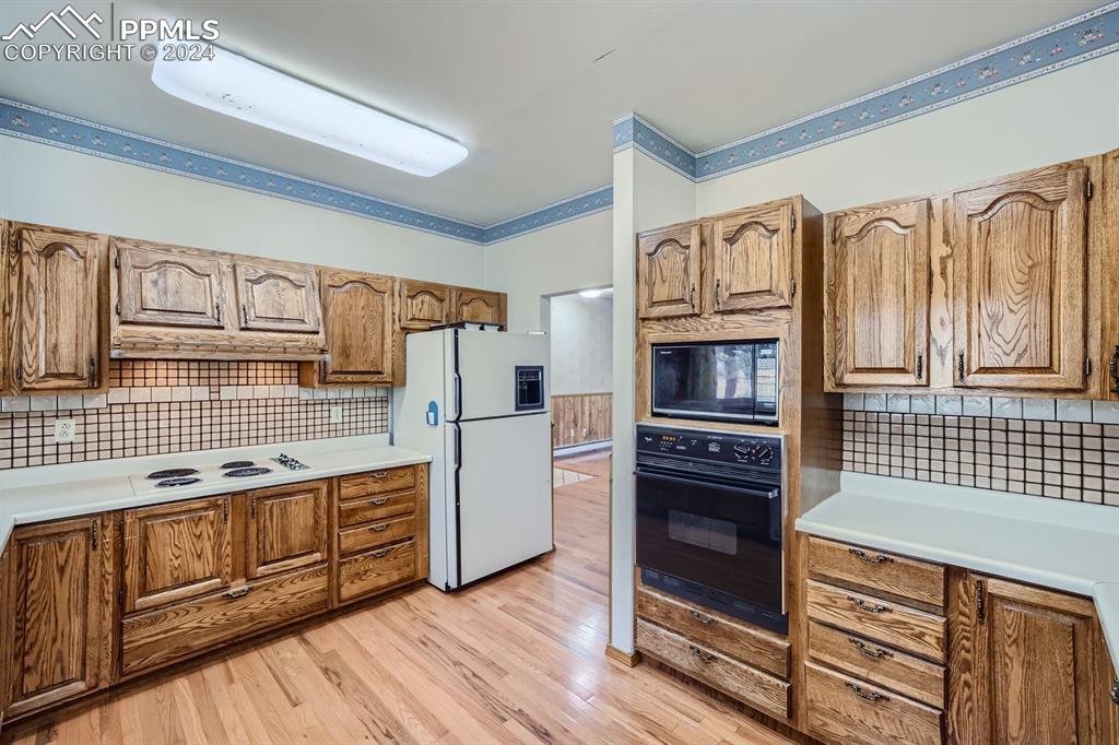11330 Holmes Road Colorado Springs, CO 80908 - Photo 8 of 40 Kitchen with tasteful backsplash, black appliances, and light wood-type flooring