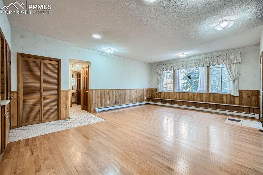 11330 Holmes Road Colorado Springs, CO 80908 - Photo 10 of 40 Spare room featuring a baseboard radiator, a textured ceiling, and light wood-type flooring