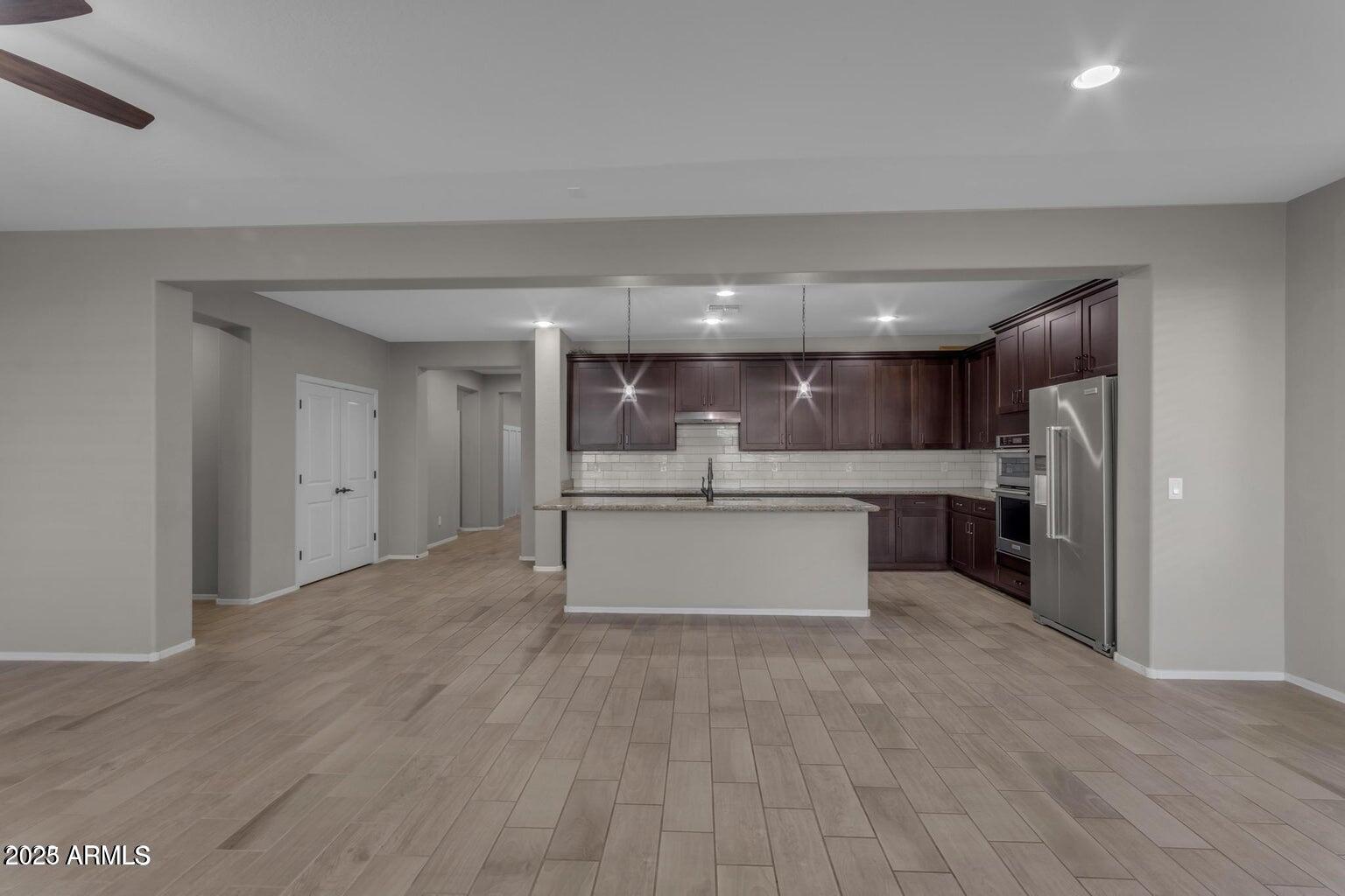 22841 South 225th Place Queen Creek, AZ 85142 - Photo 11 of 34 a large kitchen with stainless steel appliances kitchen island a large counter top and a refrigerator