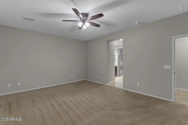 an empty room with chandelier fan and windows