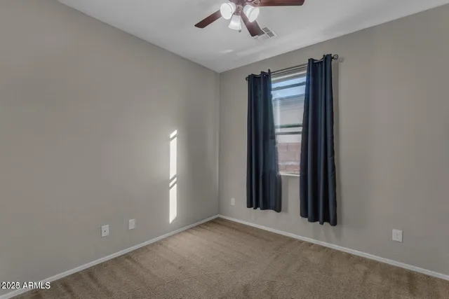 an empty room with chandelier fan and windows