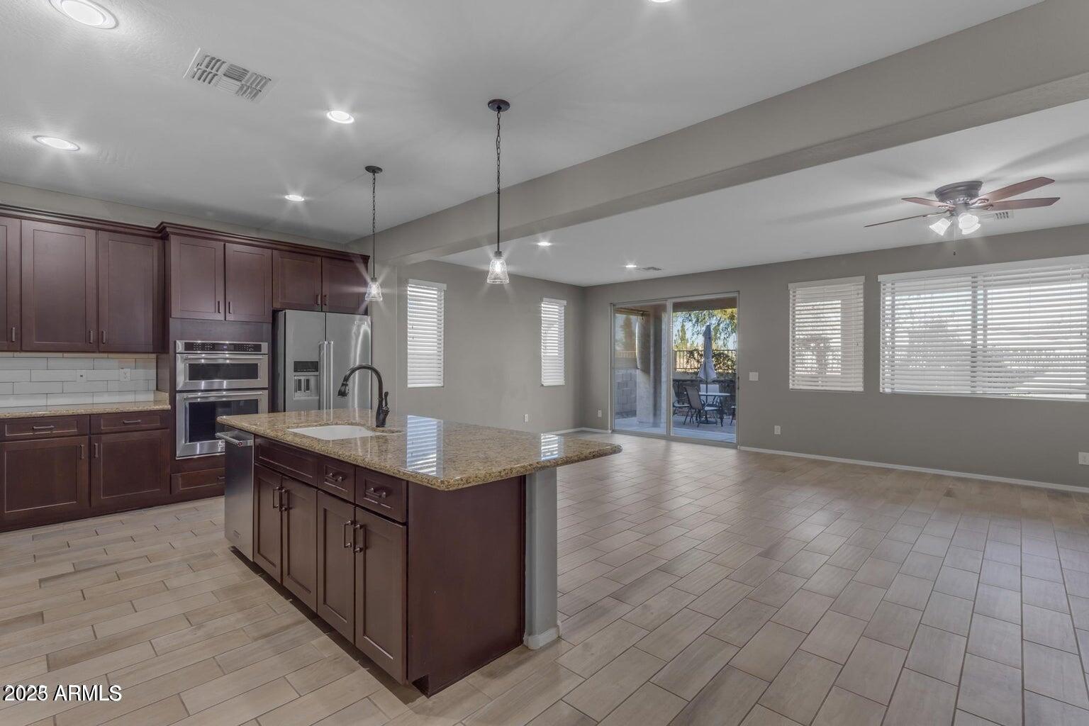 22841 South 225th Place Queen Creek, AZ 85142 - Photo 4 of 34 a kitchen with kitchen island granite countertop a sink counter top space appliances and cabinets