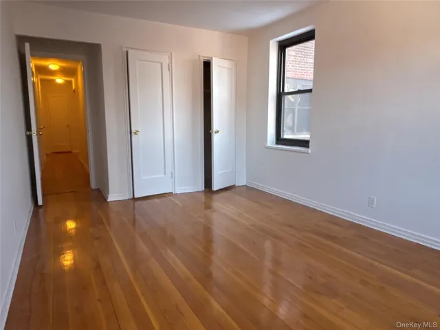 a view of empty room with window and wooden floor