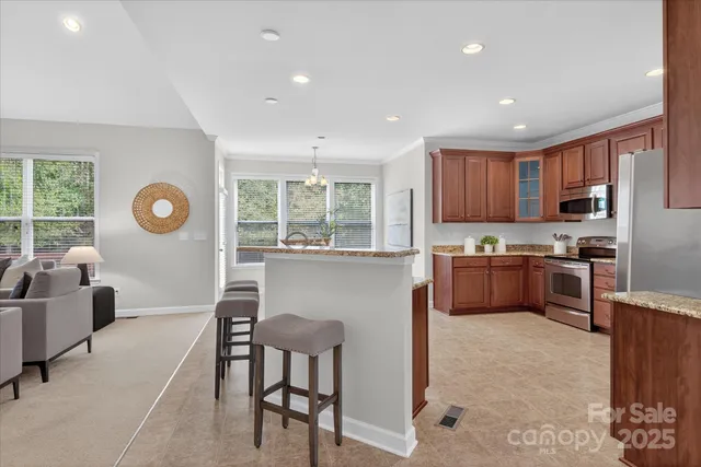 a kitchen with stainless steel appliances granite countertop a refrigerator a stove a sink dishwasher a dining table and chairs with wooden floor