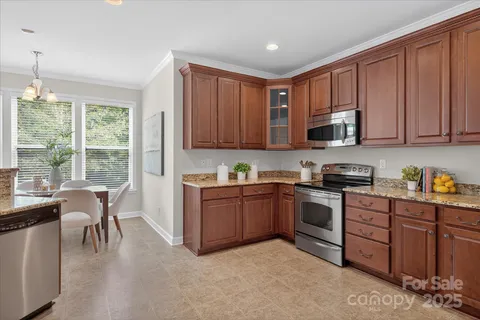 a kitchen with stainless steel appliances granite countertop a stove top oven a sink dishwasher a dining table and chairs with wooden floor