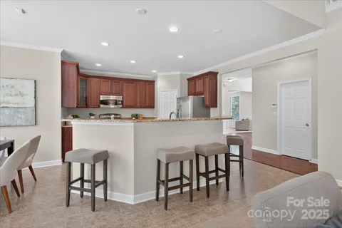 a kitchen with stainless steel appliances kitchen island granite countertop a dining table chairs and a refrigerator