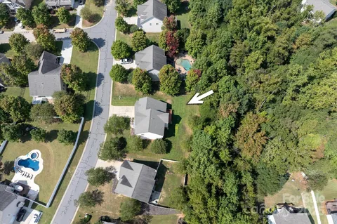 an aerial view of residential house with outdoor space and trees all around