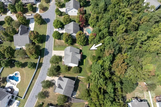 an aerial view of residential house with outdoor space and trees all around