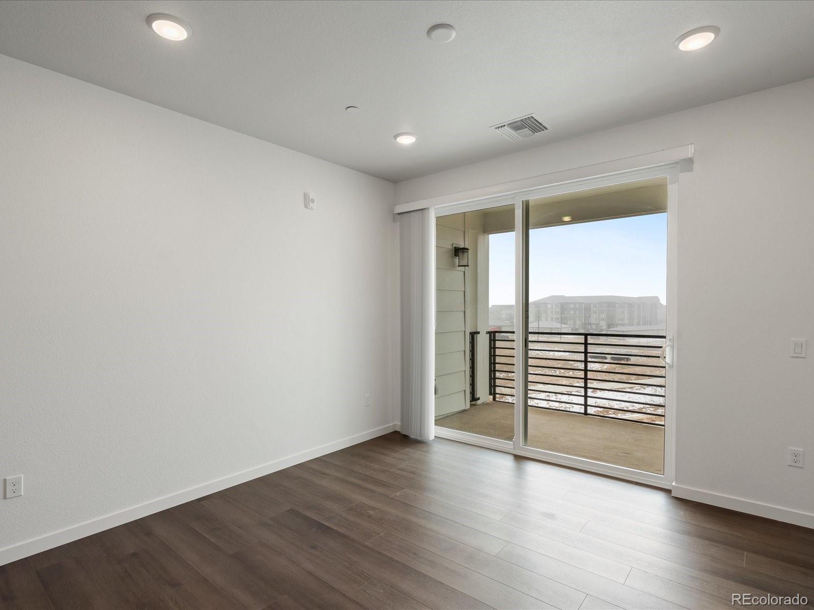 6153 North Ceylon Street, Unit 304 Denver, CO 80249 - Photo 10 of 24 an empty room with wooden floor and windows