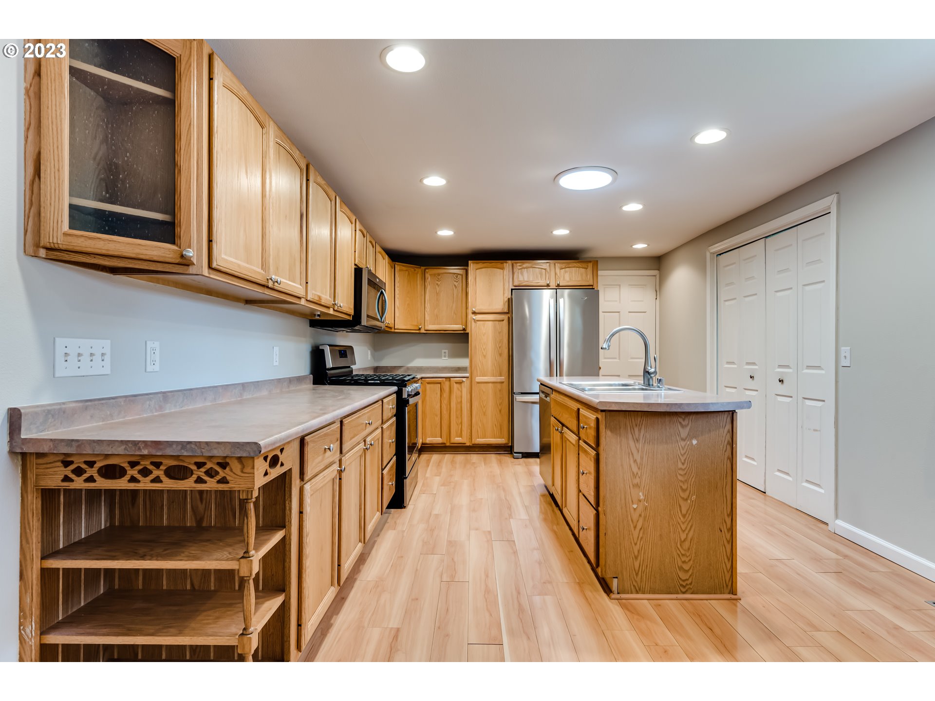 6973 Glacier Drive Springfield, OR 97478 - Photo 6 of 34 a kitchen with stainless steel appliances granite countertop a stove a sink dishwasher and a refrigerator with wooden floor