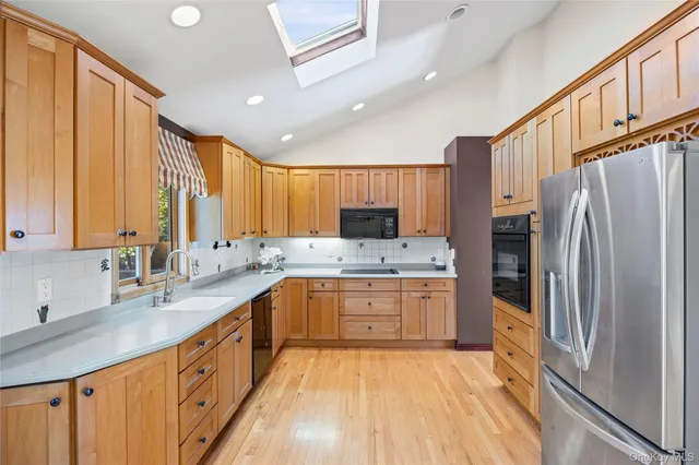 a large kitchen with stainless steel appliances granite countertop a refrigerator a sink dishwasher a stove and white countertops with wooden floor