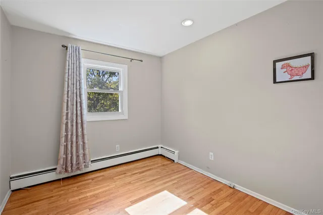 an empty room with wooden floor and window