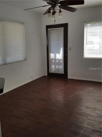 a view of empty room with wooden floor and fan