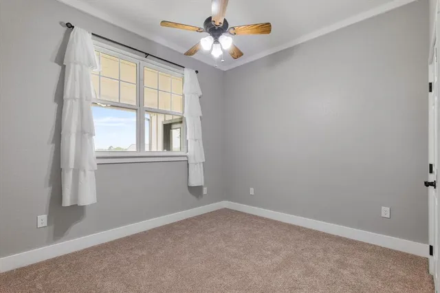 an empty room with windows and chandelier fan