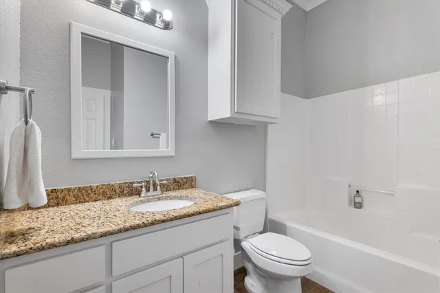 a bathroom with a granite countertop toilet a sink and a bathtub