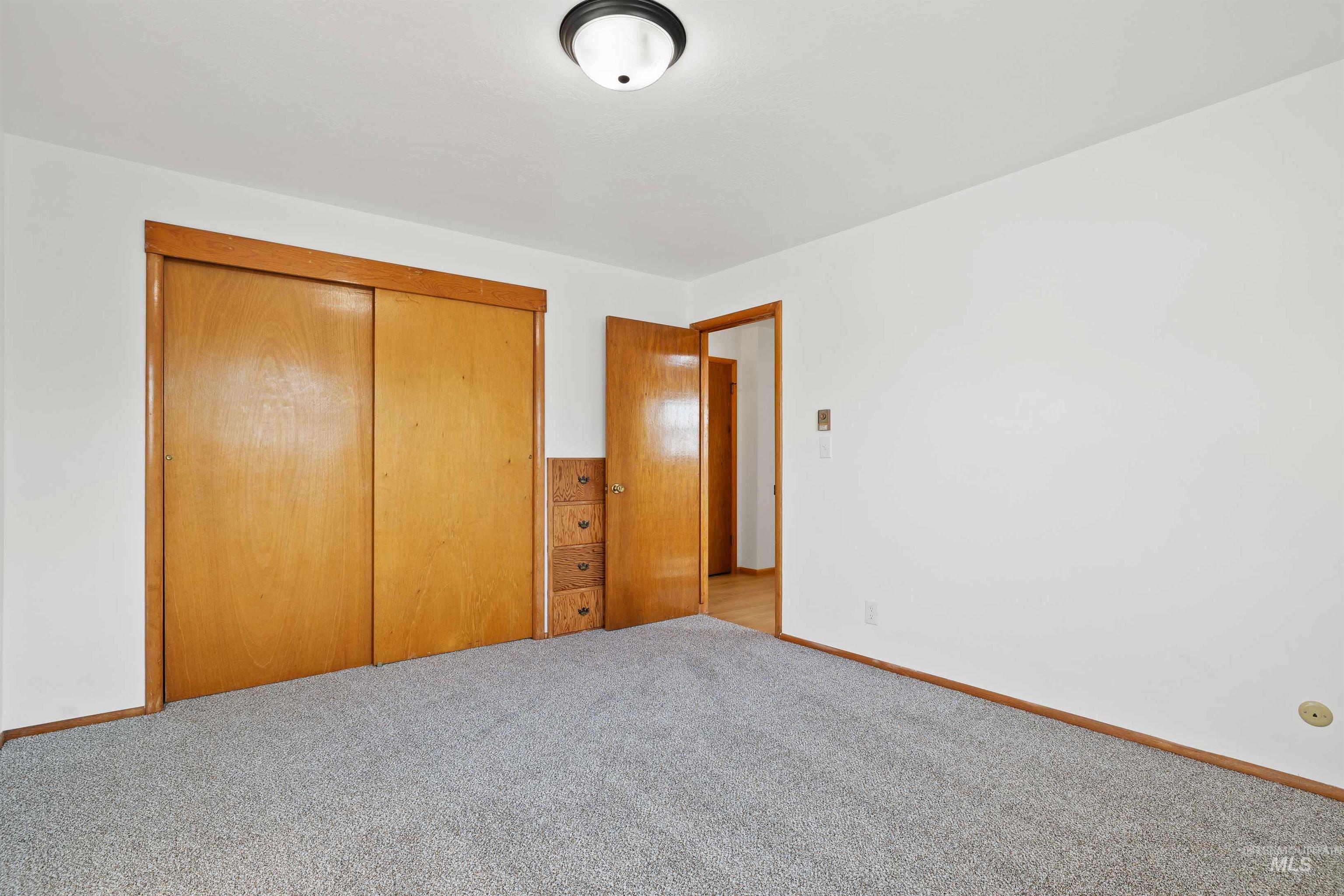321 Clear Lakes Road Buhl, ID 83316 - Photo 17 of 34 Neutral wall paint, gray carpet flooring, wood-finish sliding closet doors, wood-finish interior doors, and a flush mount ceiling light fixture