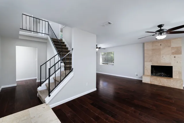 a view of an empty room with wooden floor fireplace and a window
