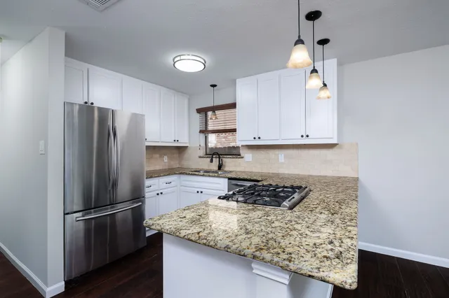 a kitchen with stainless steel appliances granite countertop a refrigerator and a stove