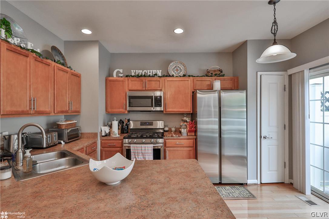 8550 Gateway Road Breinigsville, PA 18031 - Photo 16 of 50 a kitchen with stainless steel appliances granite countertop a refrigerator a stove and a sink with wooden floor