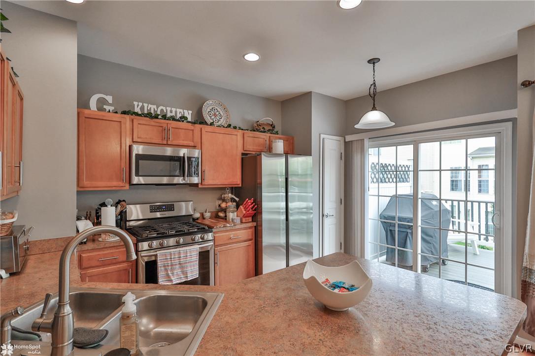 8550 Gateway Road Breinigsville, PA 18031 - Photo 20 of 50 a kitchen with stainless steel appliances a sink a stove a refrigerator cabinets and a dining table with wooden floor