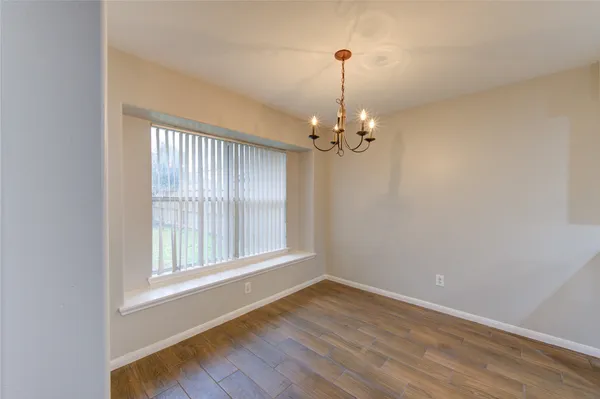 a view of empty room with wooden floor fan and window