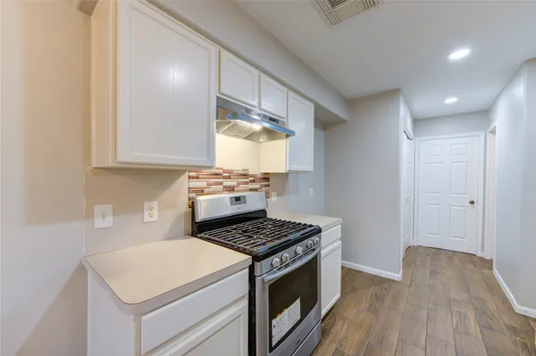 a kitchen with a stove cabinets and wooden floor