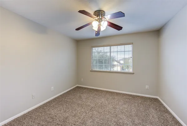 an empty room with window and chandelier fan