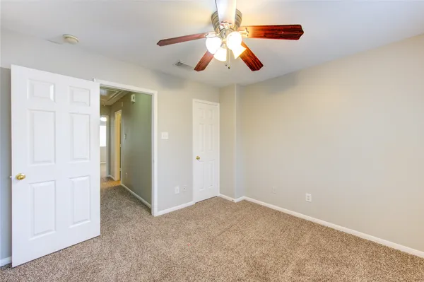an empty room with closet and a chandelier fan