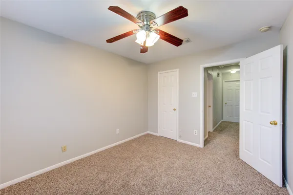 an empty room with closet and a chandelier fan