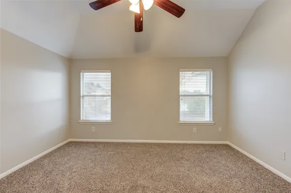 an empty room with chandelier fan and windows